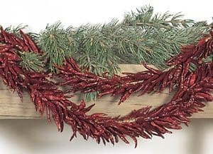 A festive mantle decoration featuring the ALL-NATURAL CHILE PEQUIN GARLAND, embellished with shiny red foliage, plaid bows, and green ornaments.