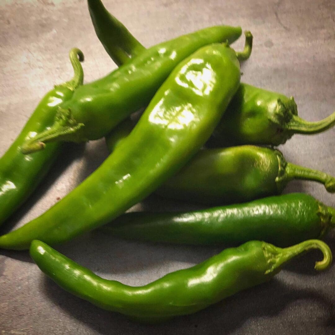 Fresh green chili peppers on a surface.