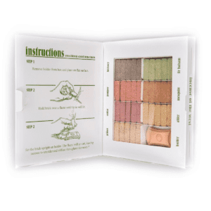 Open box of NEW MEXICO INCENSE SAMPLER displaying various colored incense bricks neatly arranged in rows, accompanied by printed usage instructions on the left.