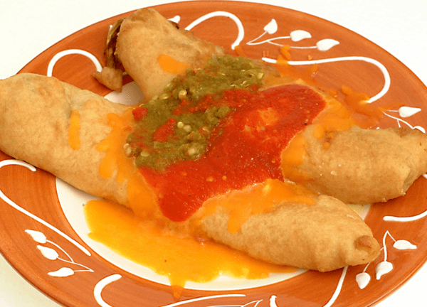 A plate featuring Chiles Rellenos, stuffed and fried tortillas topped with rich red and green salsa and melted cheese in the center. Package of four.