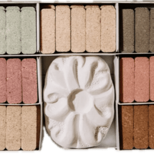 Various pastel and neutral color chalks in organized boxes with a carved white chalk centerpiece.