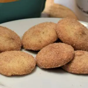 A white plate topped with several cookies covered in sugar.