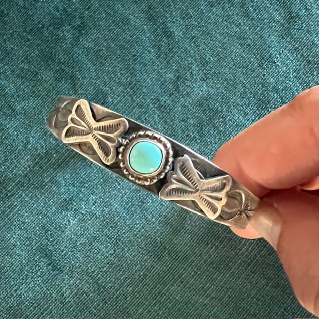 Silver ring with turquoise stone and engraved cross designs.