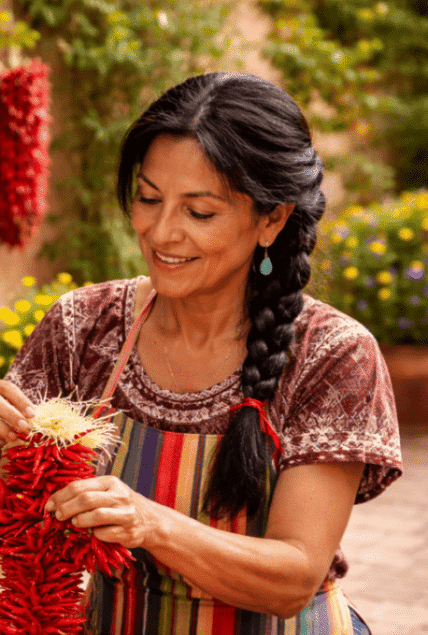Smiling woman stringing red chili ristras